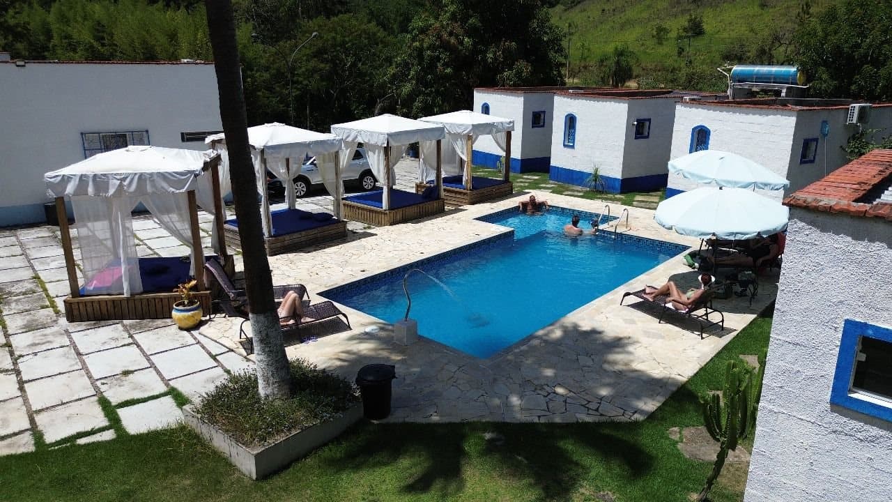 Piscina, cabanas e chalés brancos com janelas azuis da Pousada Santorini